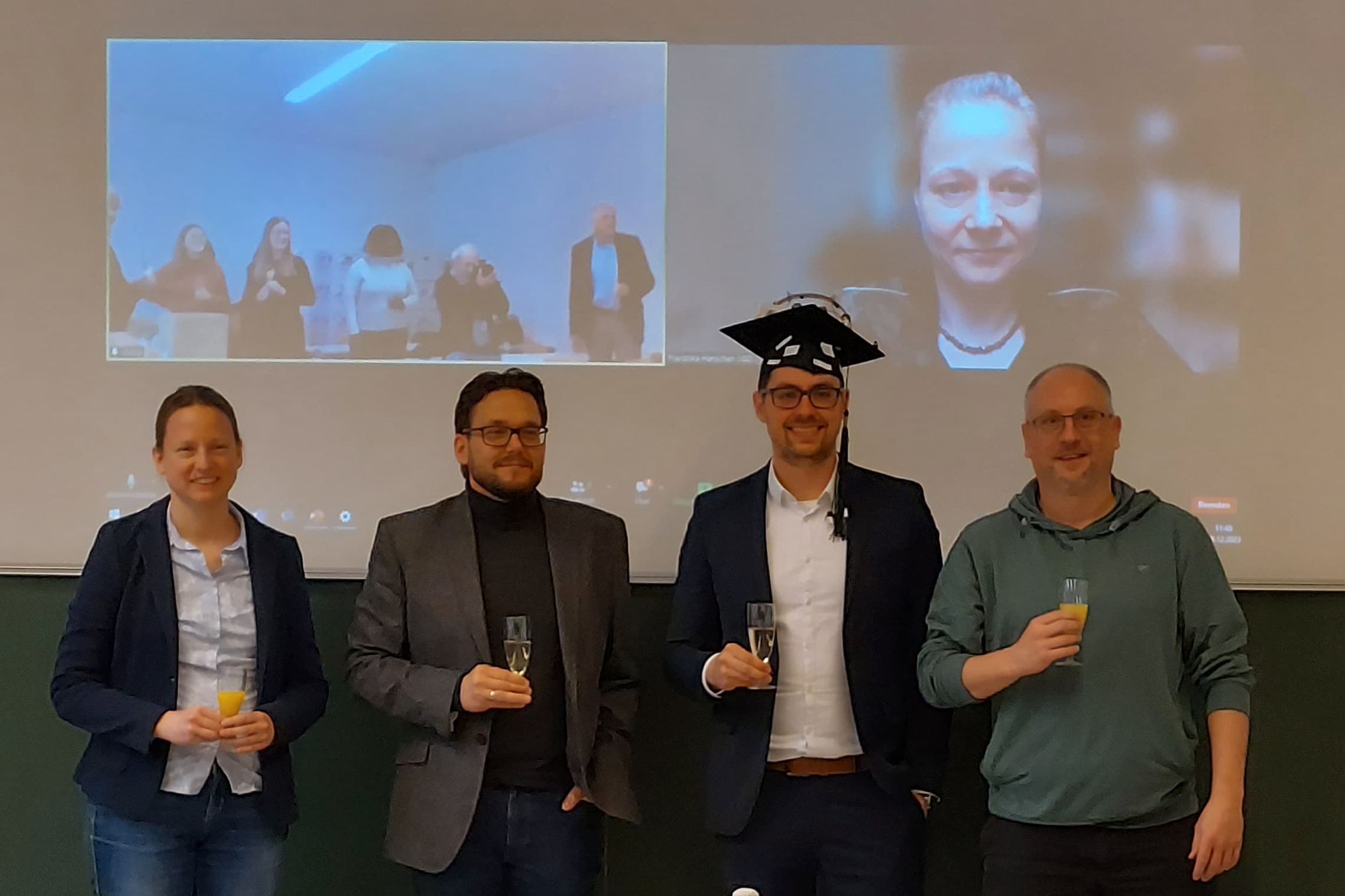 Renz toasts with the reviewers and the chairwoman: from left to right Prof Dr Cornelia Rauh, Prof Dr Hajo Haase, Dr Matthias Renz, Prof Dr Sascha Rohn. In the background Dr habil. Franziska Hanschen